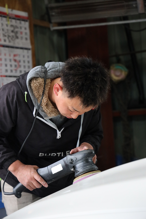 GATの作業者が車体の表面に向き合う作業風景